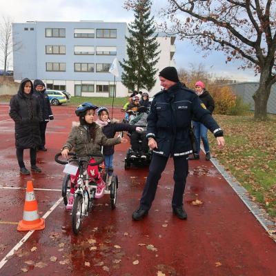 Der Polizist zeigt den Schülerinnen, wie man Handzeichen auf dem Fahrrad gibt