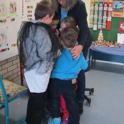 4 Erstklässler, 3 Jungen und ein Mädchen, stehen eng gedrängt vor ihrer Klassenlehrerin. Sie spielen nach, wie Pinguine sich gegenseitig wärmen.
