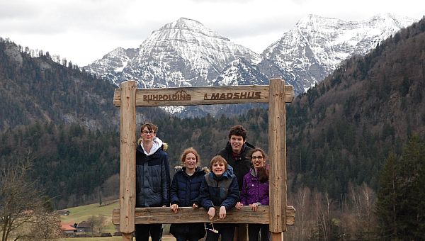Vor einem schönen Bergpanorama steht ein hölzerner Rahmen. Darauf steht „Ruhpolding Madshus“. Im Rahmen stehen Florian, Lara, Christopher, Julian und Marija. Sie lächeln in die Kamera.