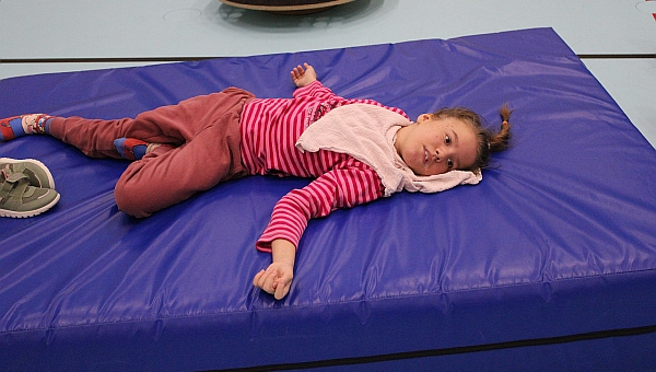 Eine Schülerin liegt entspannt auf der blauen großen Matte