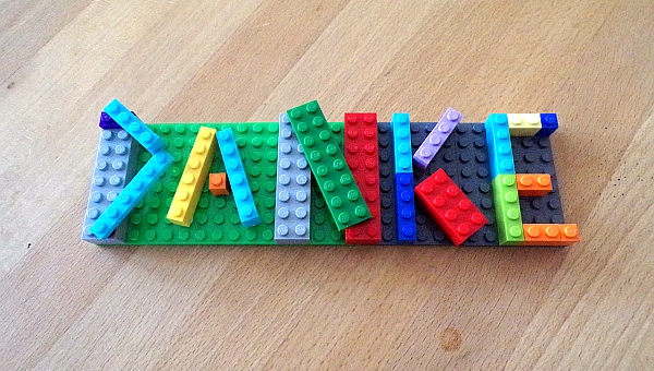 Auf dem Foto ist das Wort Danke zu sehen. Es wurde aus vielen bunten Lego Steinen zusammengesetzt. 
