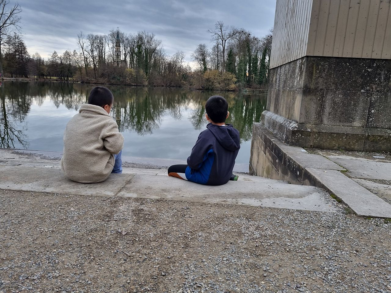 Zwei Jungen sitzen am See und schauen in das Wasser