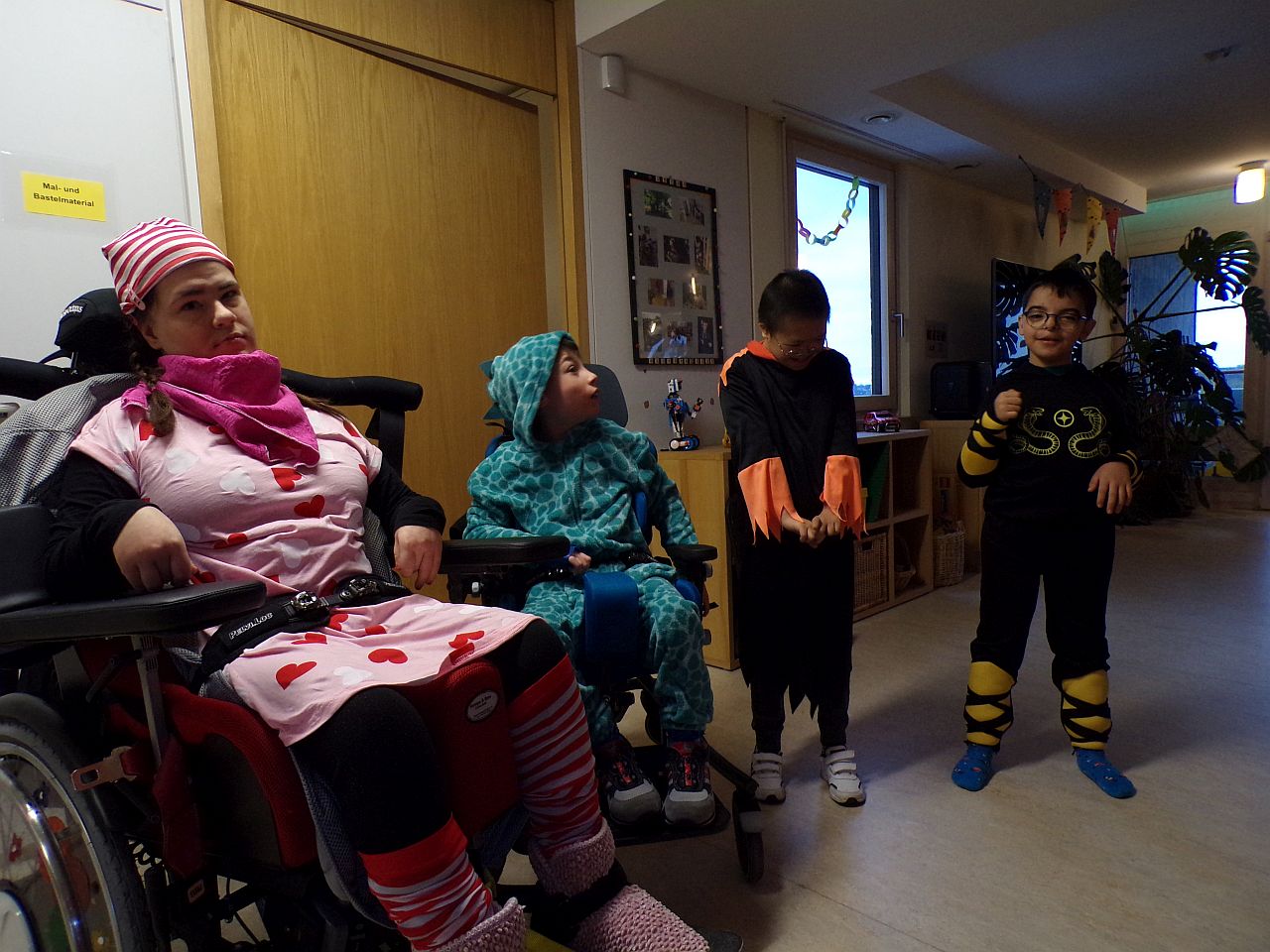 Es sind 4 Kinder zu sehen. Links ein Mädchen verkleidet als Schlafmütze im Schlafanzug. Daneben ein Junge in grünem Dinosaurierkostüm.