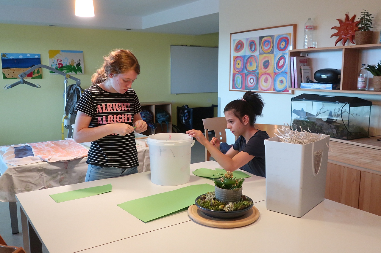 Zwei Mädchen schneiden kleine Papierschnipsel