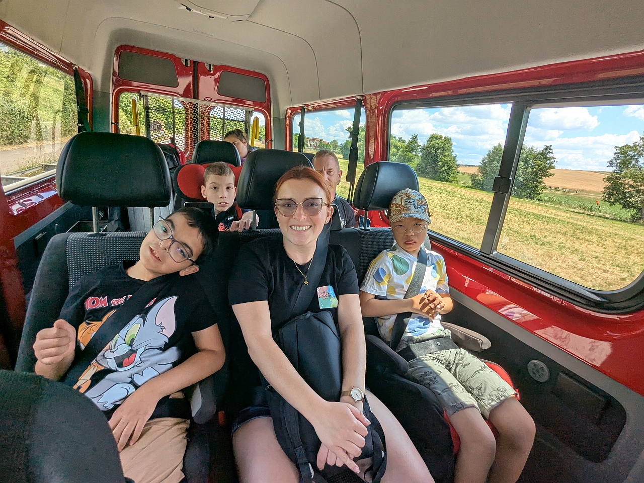 Eine Gruppe von Schülern und Schülerinnen sitzen zusammen mit zwei Betreuern in einem Bus.  