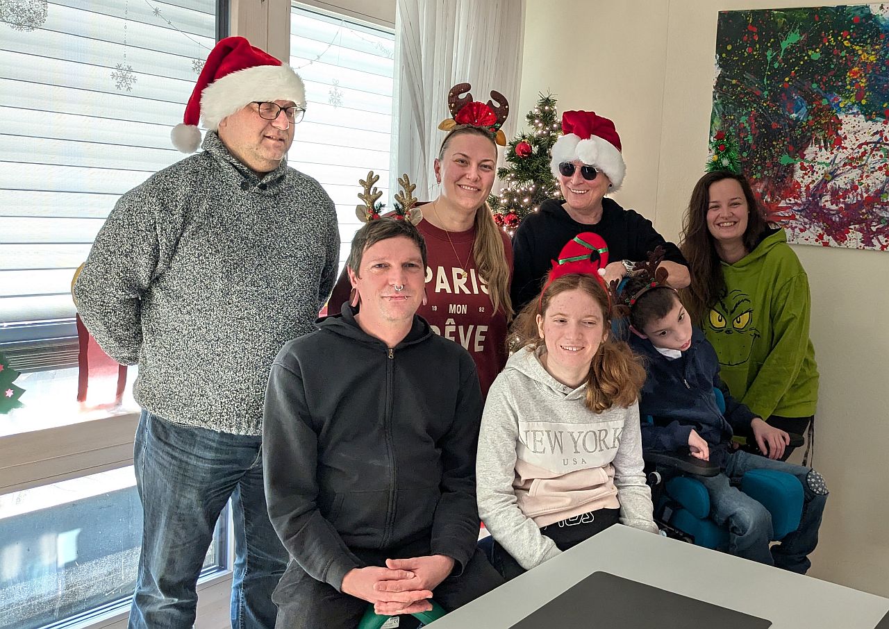 2 Männer und 3 Frauen haben weinachtlichen Haarschmuck auf dem Kopf und lachen in die Kamera