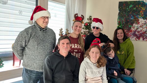 2 Männer und 3 Frauen haben weinachtlichen Haarschmuck auf dem Kopf und lachen in die Kamera