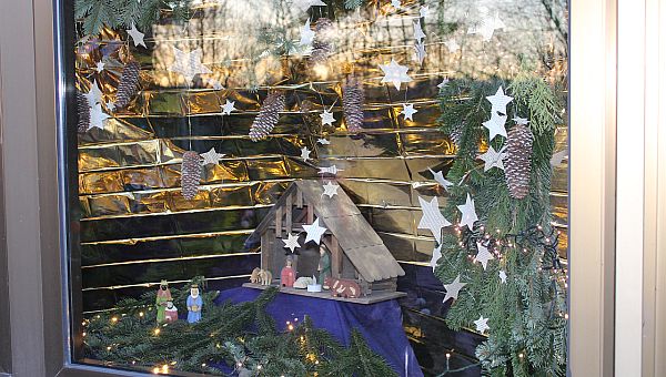 Eine Weihnachtsgrippe steht in einem schön geschmückten Fenster