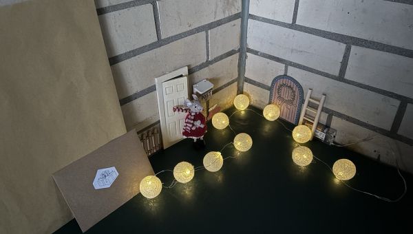 Ella steht vor der Türe, ein Briefkasten ist zu sehen.