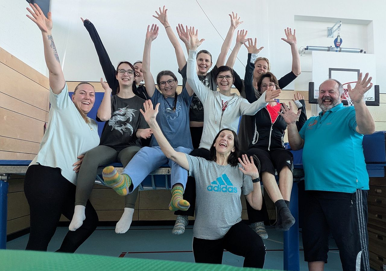 Gruppenbild mit 11 Peronen, alle lachen und strecken die Arme in die Luft
