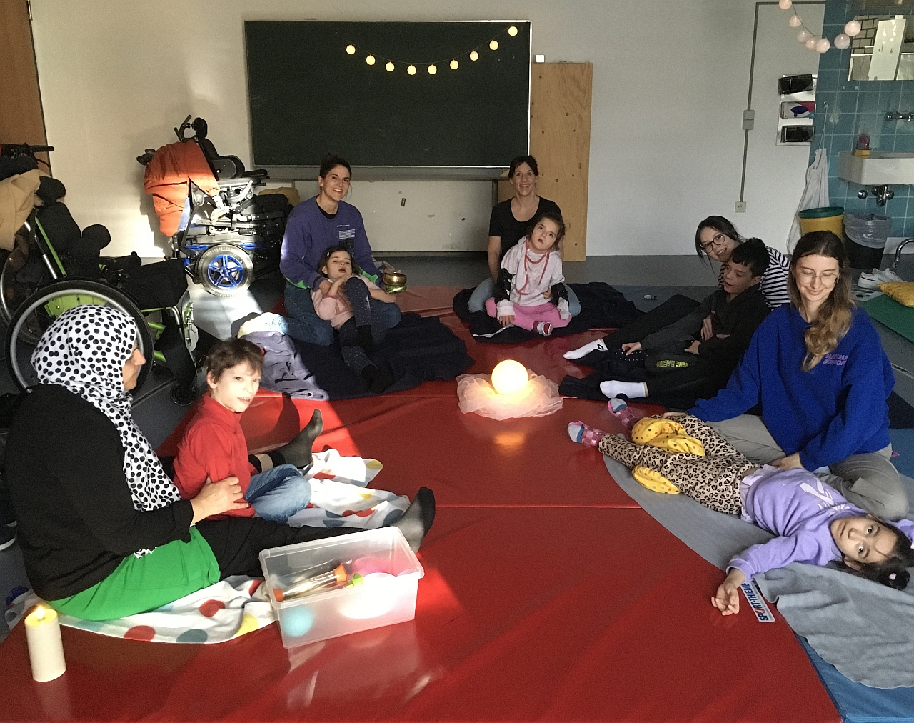 Die Schülerinnen und Schüler der Yoga-AG sitzen oder liegen im Kreis. Wir beginnen mit unserer Yoga-Zeit. Wir haben Besuch von Jara Alber. 