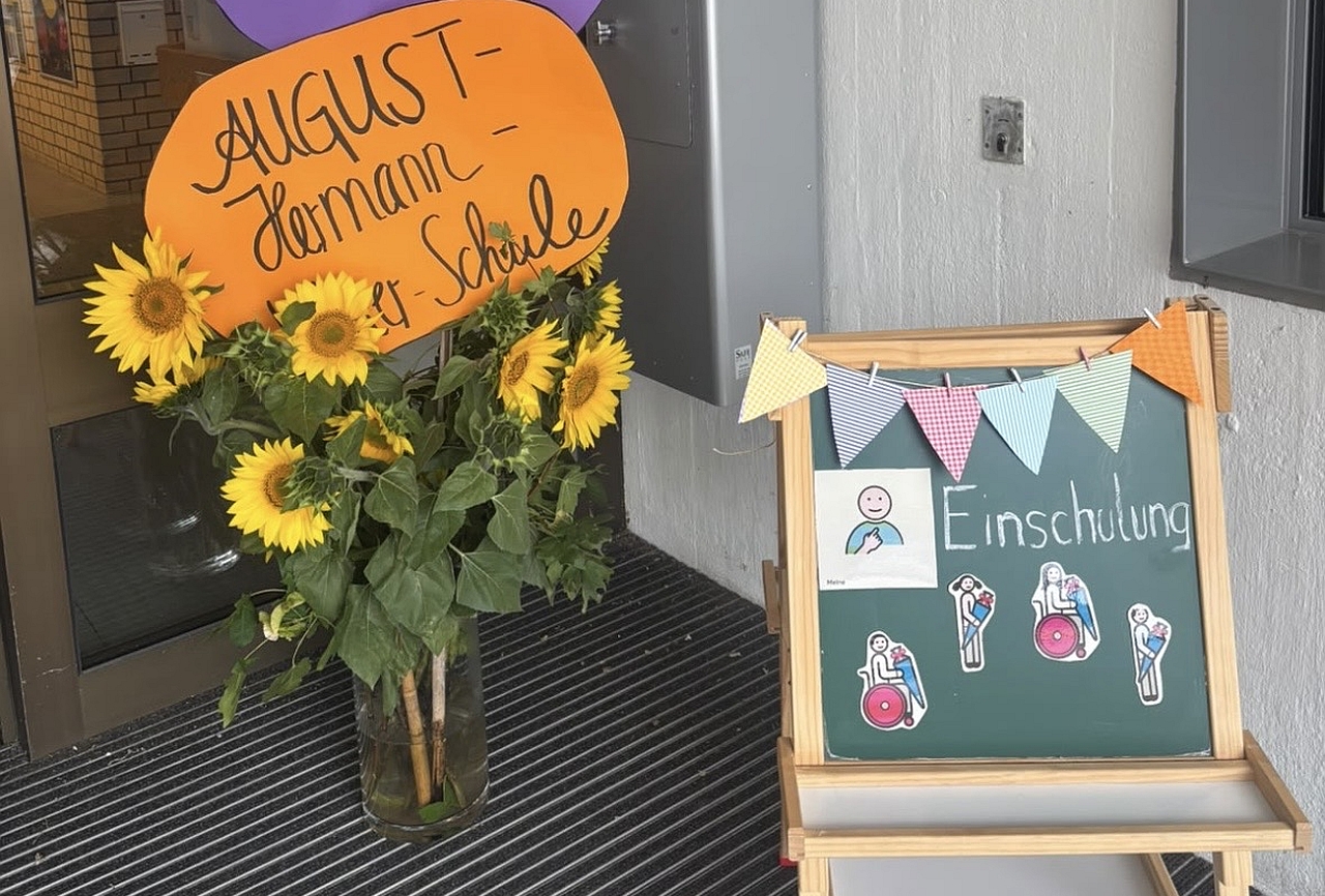 Begrüßung der neuen Erstklässler*innen durch gebastelte Schilder und Blumen vor dem Schuleingang. 