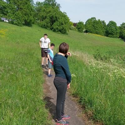 3 Schüler bei der Wanderung bei Sonnenschein auf einem Feldweg