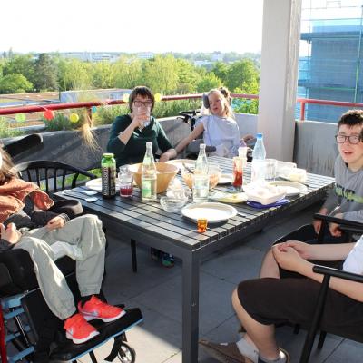 Bei Sonnenschein sitzen fünf Schüler auf dem Internatsbalkon mit gedecktem Tisch 