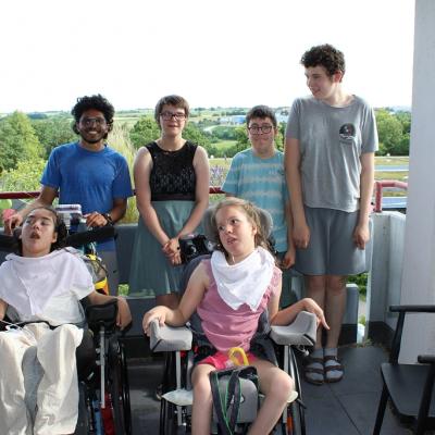 2 Rollstuhlfahrer, drei stehende Schüler und ein Betreuer auf dem Balkon