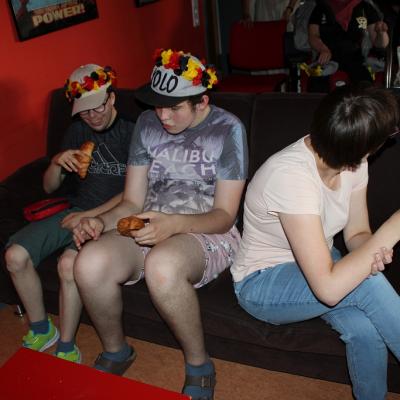 Drei Schüler sitzen auf dem Sofa , schauen Fußball auf der Leinwand und essen 