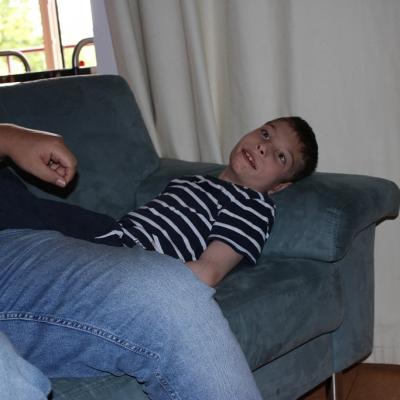 Ein Schüler liegt entspannt auf dem Sofa , neben einem Betreuer