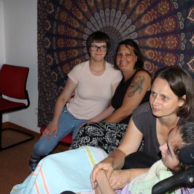 Eine Schülerin umarmt eine Betreuerin, eine Rollstuhlfahrerin hält eine Betreuerin fest