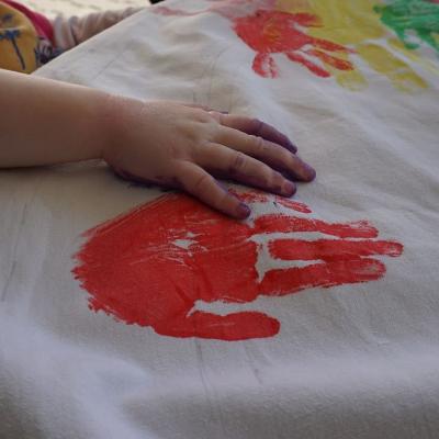 Eine kleine Hand auf einem bedruckten Tuch.