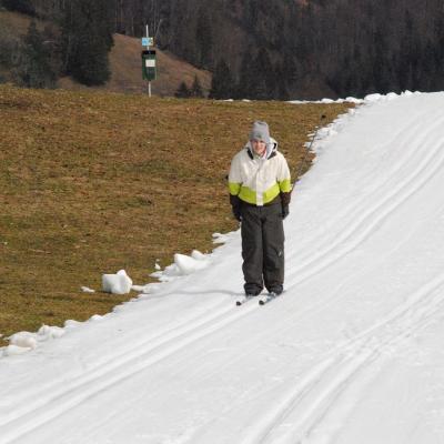 Julian fährt eine Loipe bergab. Links neben der Loipe sieht man eine Grasfläche.