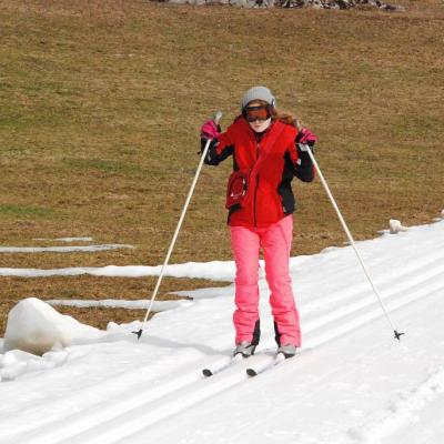 Lara fährt eine Loipe bergab. Links neben der Loipe sieht man eine Grasfläche.