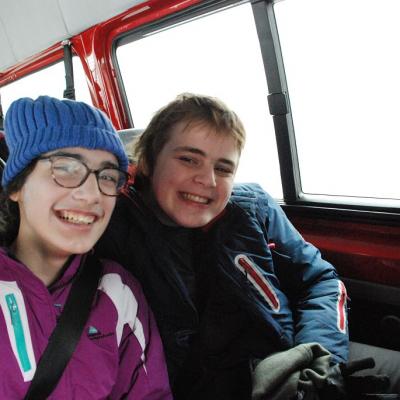 Marija und Christopher sitzen im Bus und lächeln in die Kamera.