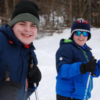 Christopher und Josua stehen im Schnee und lächeln in die Kamera.