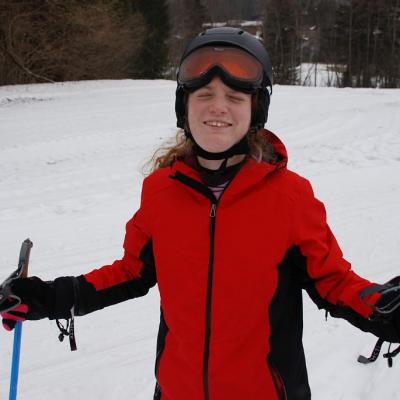 Lara steht im Schnee und lächelt in die Kamera.