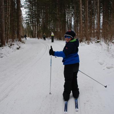 Josua läuft in der Loipe und dreht sich lächelnd nach hinten zur Kamera.