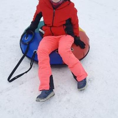 Lara sitzt in einem blau rot, gelb grünen Schlauchreifen und lächelt. 