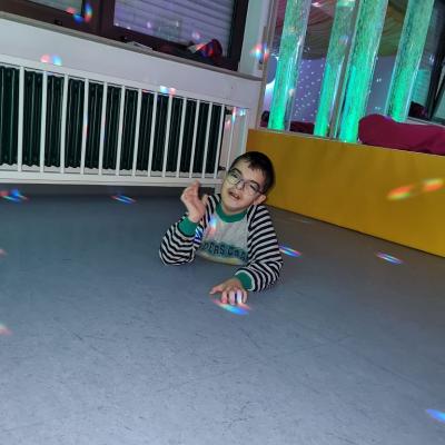 Ein Junge liegt entspannt auf dem Boden und beobachtet die Lichter die sich bewegen.