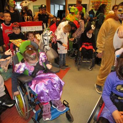 Fasching in der Schulaula, ca. 15 bunt verkleidete SchülerInnen und Mitarbeitende warten auf den Beginn der Feier