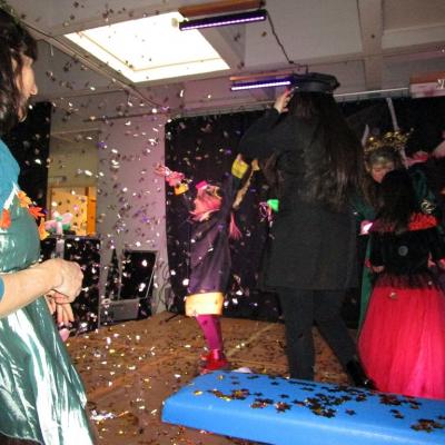 Fasching in der Schulaula, im Konfettiregen tanzendes Mädchen im Grundschulalter