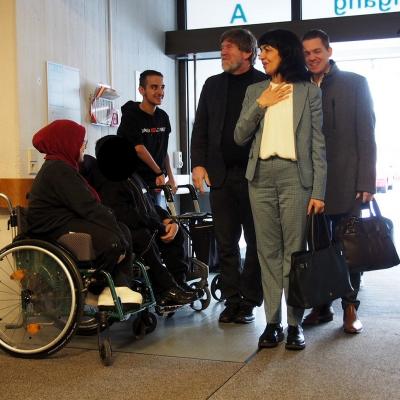 Frau Aras betritt mit Herr Dr. Rößler und Herr Klecker das Schulgebäude. Sie werden von Schülern im Spalier begrüßt. Frau Aras lacht und wirkt gerührt.
