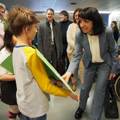 Ein Schüler hält ein Plakat hoch. Frau Aras spricht mit dem Schüler. Im Hintergrund sind Frau Fißler, Herr Klecker und Herr Dr. Rößler zu sehen.