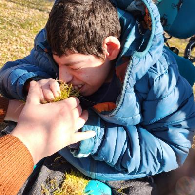 Ein Schüler im Rollstuhl  riecht an der Mooskugel