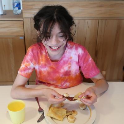 Ein Mädchen hält einen Pfannkuchen in ihren Händen und lächelt.