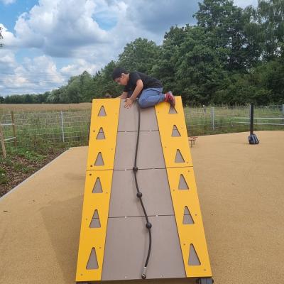 Ein Junge sitzt auf der Spitze einer Kletterwand.  