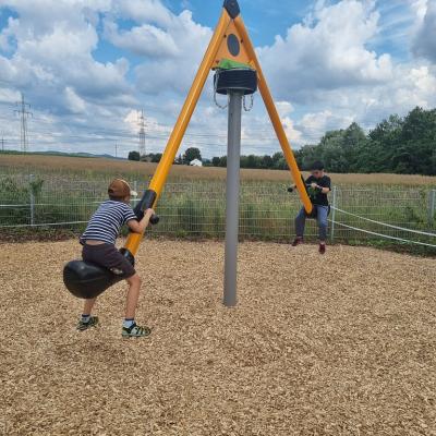 Zwei Jungen sitzen auf einer hohen Wippe. 