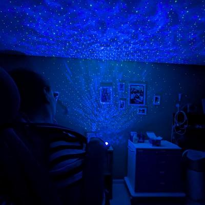 Ein Mädchen schaut in einen abgedunkelten Raum. Der Raum ist erfüllt von einem blauen Sternenhimmel.  