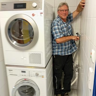 Ein Hausmeister montiert einen Wasseranschluss für eine Waschmaschine