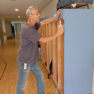 Ein Hausmeister hämmert einen Nagel in ein Regal