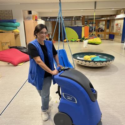 Eine Reinigungskraft arbeitet mit einer Reinigungsmaschine