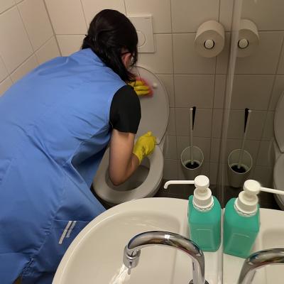 Eine Reinigungskraft reinigt ein WC-Becken