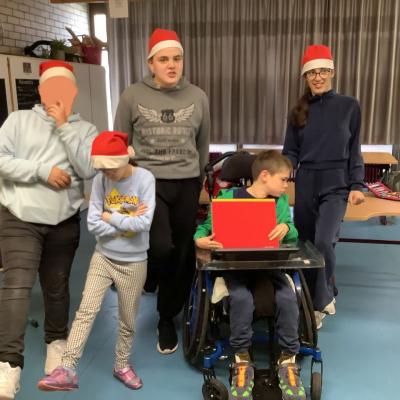 Auf dem Foto sind 3 Schüler und 2 Schülerinnen in Weihnachtsmützen zu sehen. Sie strecken ein Bein oder heben ein Bein an. Ein Schüler zeigt ein rotes Schild. 