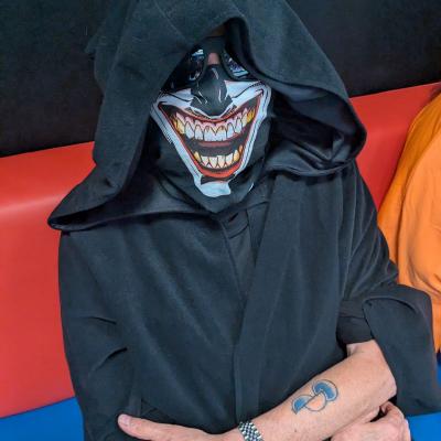 Eine Frau mit einem gruseligen Geisterkostüm sitzt auf einer Bank und schaut in die Kamera