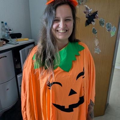 Eine Frau im Kürbiskostüm lächelt in die Kamera