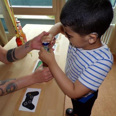 Ein Junge öffnet mit Hilfe eine Flasche.