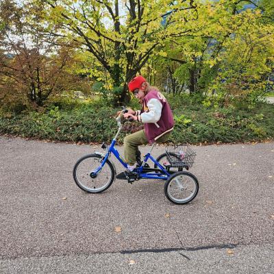 Schülerin fährt mit ihrem blauen Fahrrad mit drei Rädern über den Stein Boden