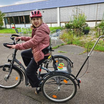 Schülerin fährt mit Fahrrad Helm auf ihrem Fahrrad und schaut lächelnd in die Kamera.